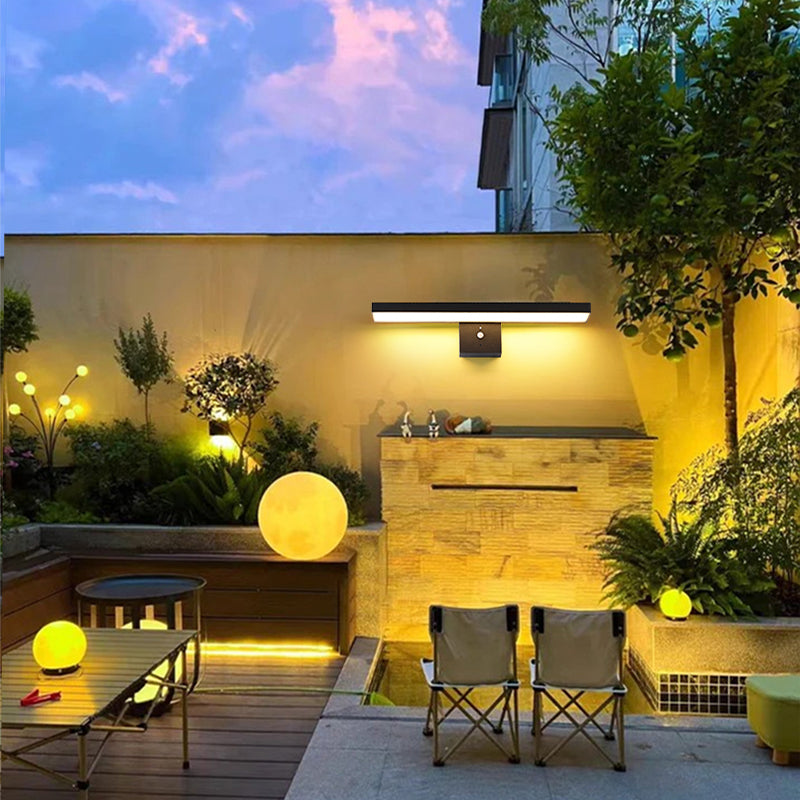 Modern outdoor patio with lighting, chairs, and a water feature.