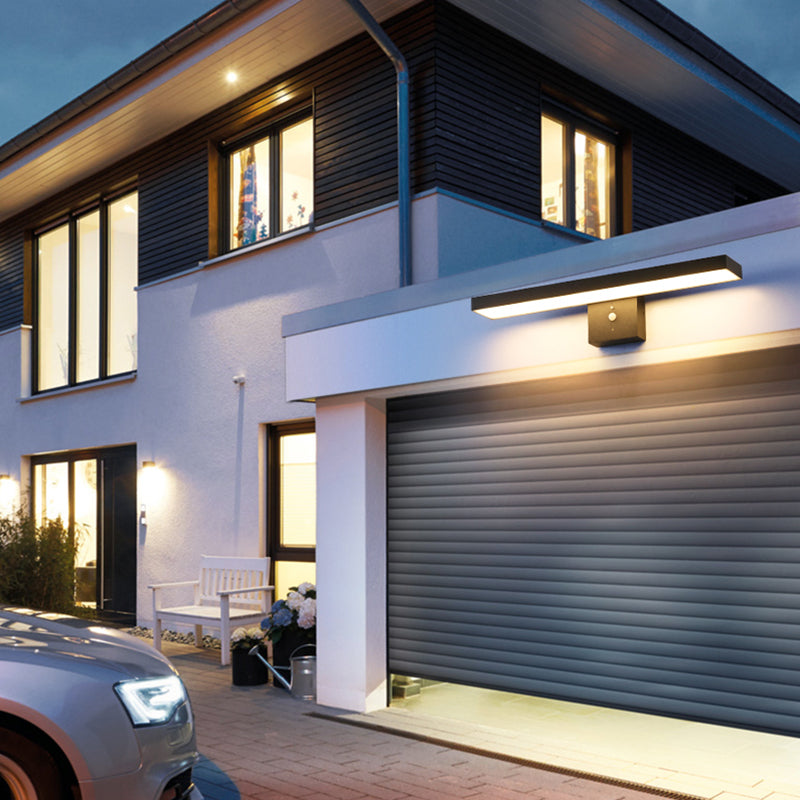 Modern house exterior with a garage and wall-mounted light fixture.